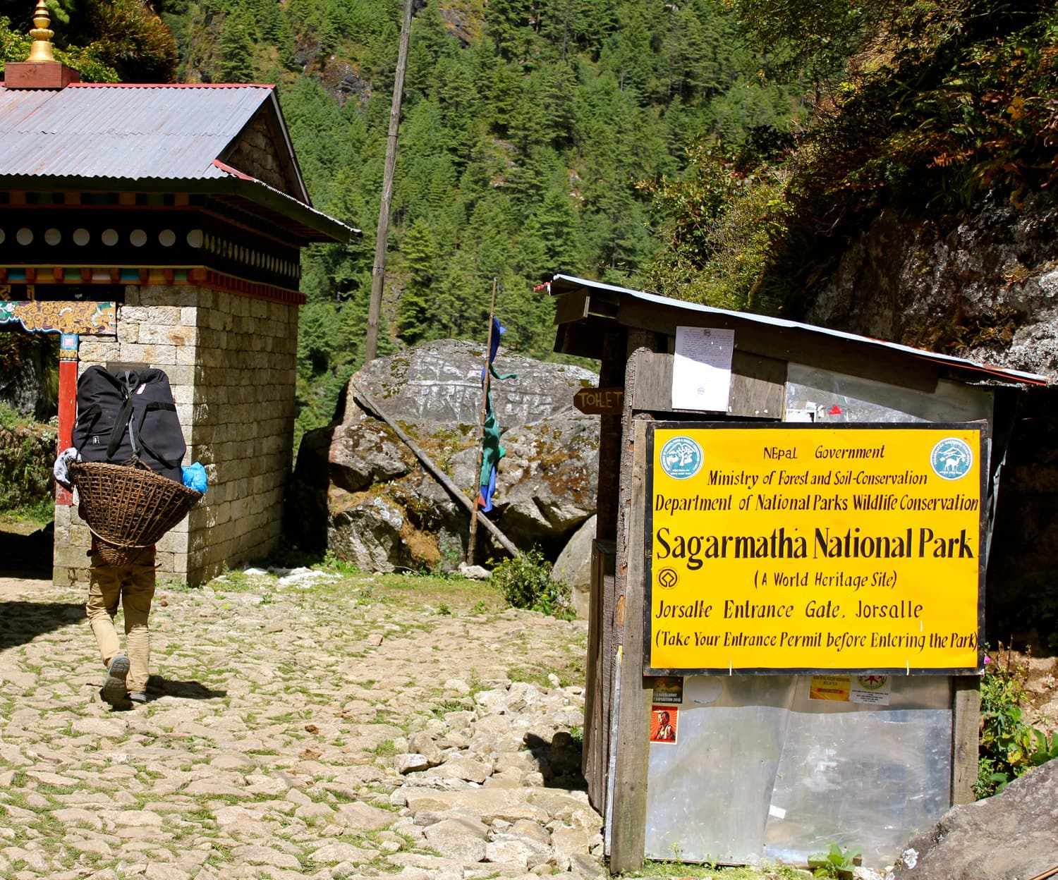 Ein Träger geht am Eingangsschild des Sagarmatha-Nationalparks am Jorsalle-Tor vorbei